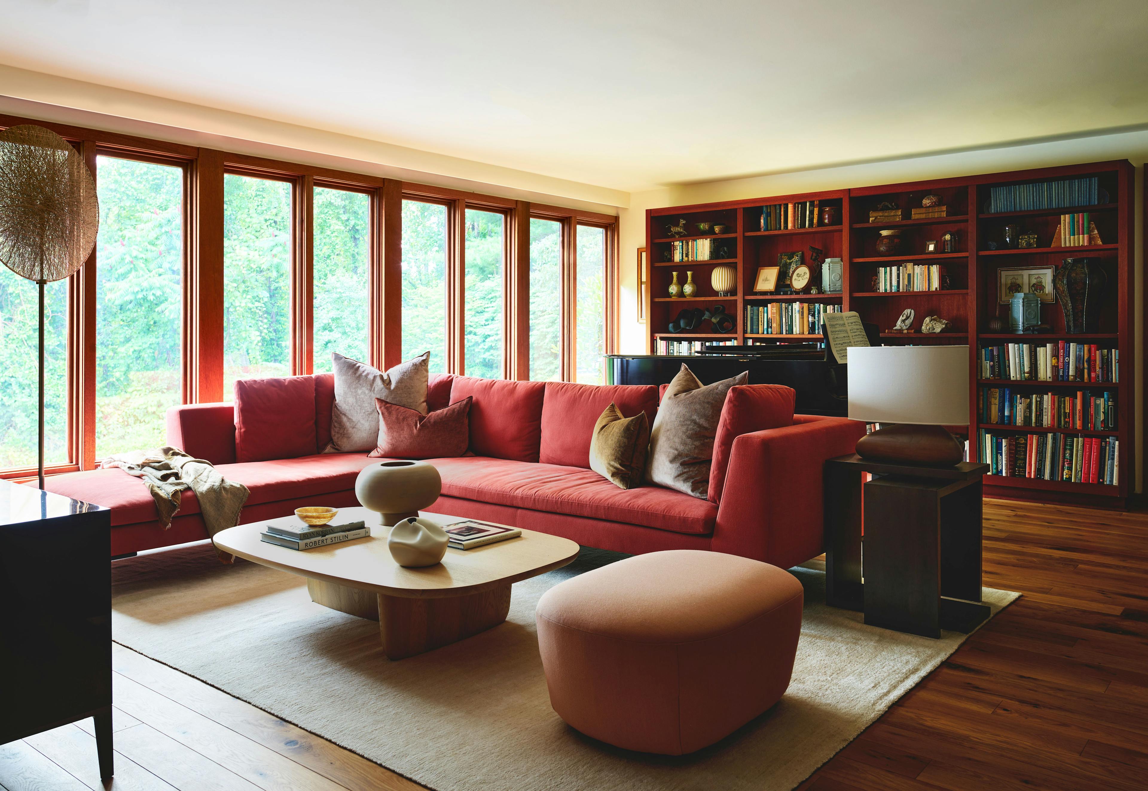 A living room with a red couch and a coffee table in the Amherst Residence, blending old antiques with contemporary pieces in a mountain landscape setting.