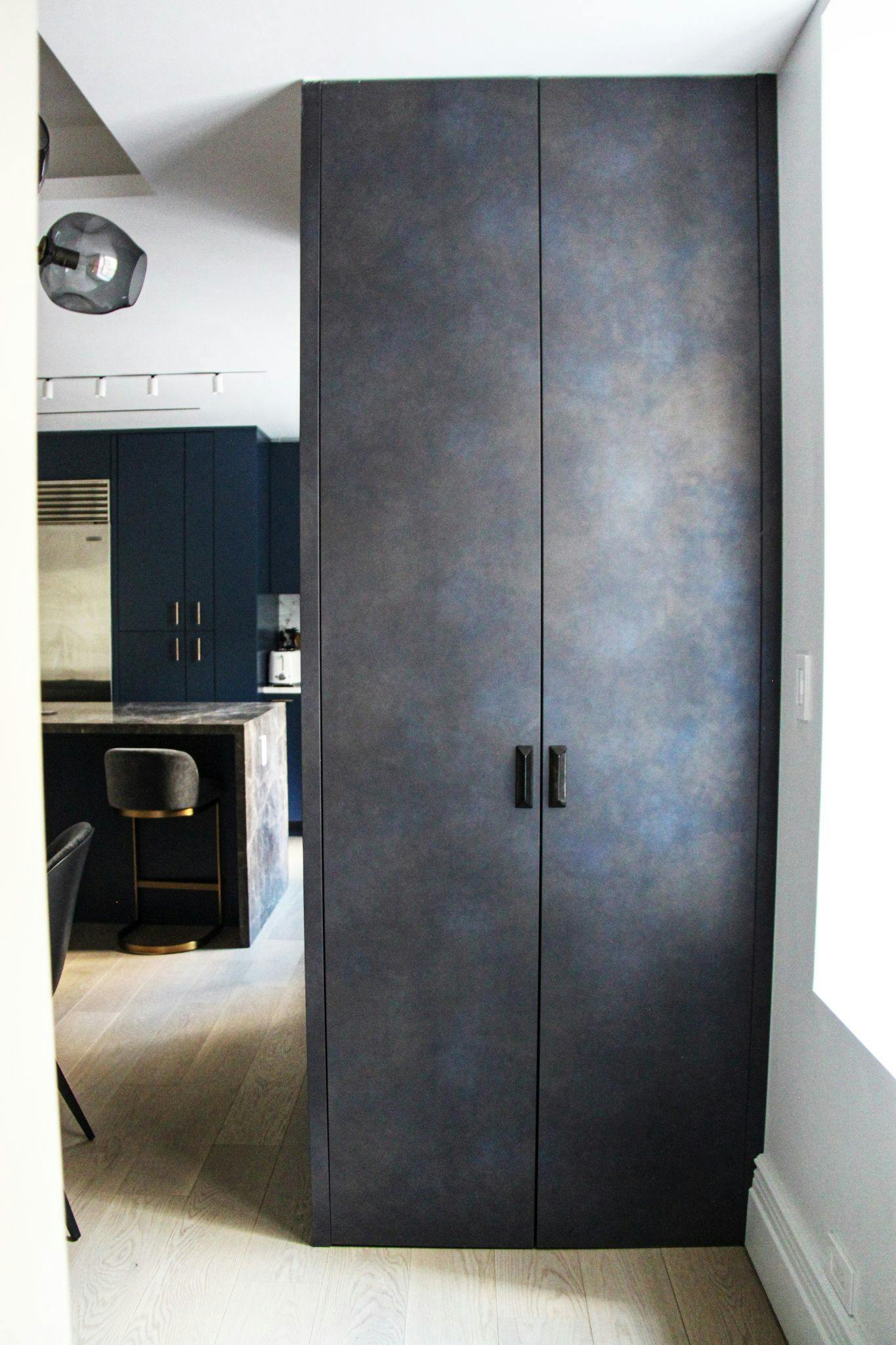 A dark blue kitchen with a black cabinet.